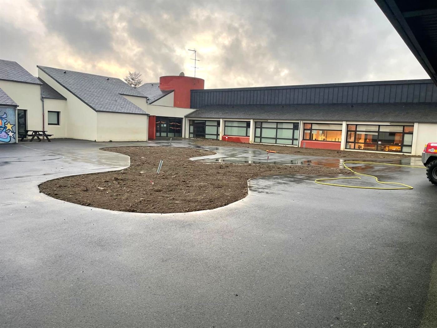 Cour d'école terminée avec des massifs de terre aux bords arrondis au milieu de l'enrobé