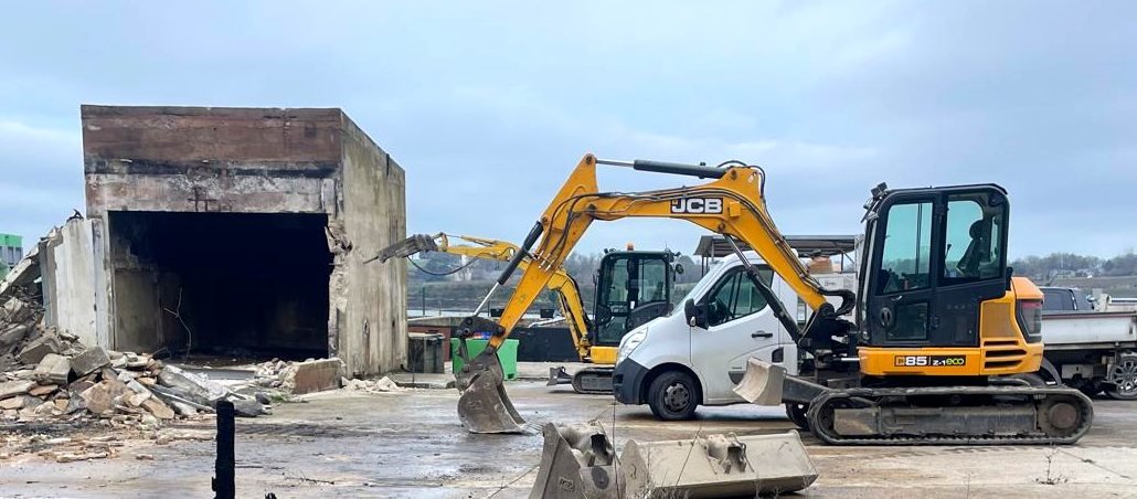 Une pelle et une mini-pelle travaillant ensemble à la démolition d'un bâtiment en béton