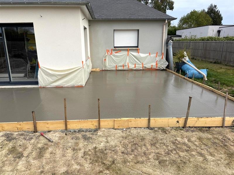Dalle de terrasse en béton fraîchement coulée au pied d'une maison