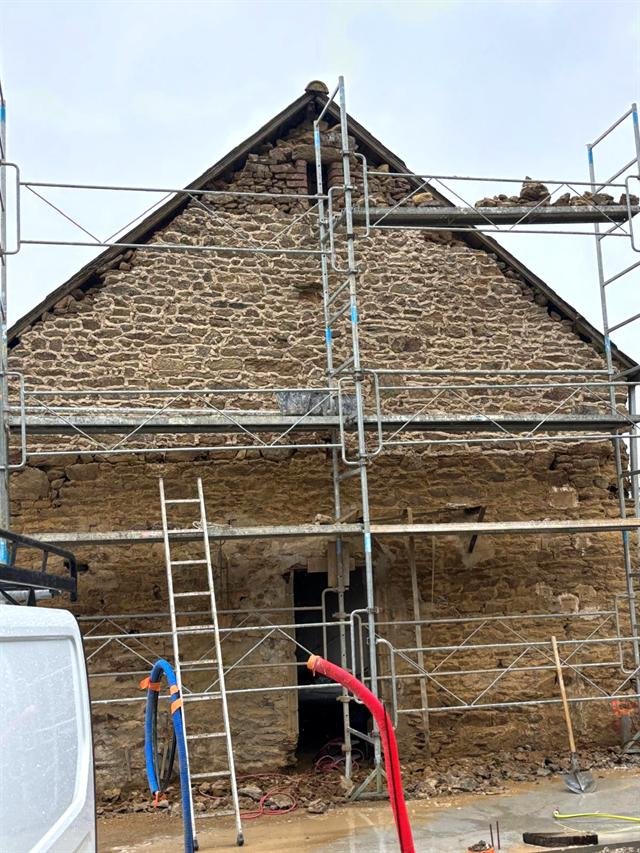 Pignon de maison en pierre sous échafaudage, avec les joints refaits